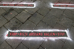 Auf den Asphalt aufgebrachter Schriftzug "Abstand halten". Foto: Nika Kramer