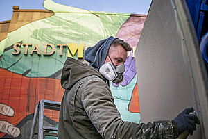 Wandmaler bei der Arbeit am Fassadengemälde "Etikette". Foto: Nika Kramer